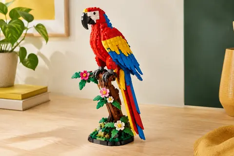 Perroquet LEGO coloré articulé posé sur une branche fleurie, construit avec des briques multicolores.